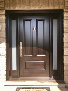 the front door to a home with a welcome mat on the ground and a brown wooden door