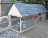 a chicken coop in the back yard with gravel and rocks around it's perimeter