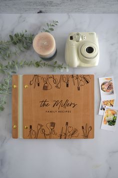 a wooden notebook sitting on top of a table next to a camera and some photos