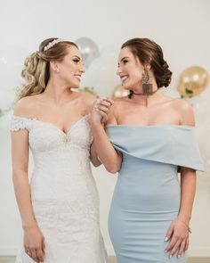 two women standing next to each other in front of balloons and confetti on the wall