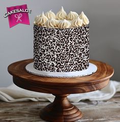 a leopard print cake with white frosting on a wooden stand