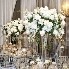 there are many tall vases with white flowers in them on the tables at this wedding reception