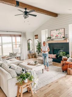 a woman standing in the middle of a living room with white walls and wood floors