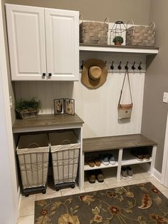 a mud room with white cabinets and baskets