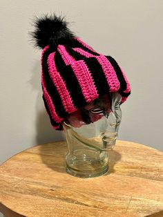 "This adult crochet hat is made with 100% quality acrylic yarn in bright pink and black stripes. Fits average adult head sizes between 20-22\". Black pom pom is attached and complements the colors of the hat.   Spot clean only by hand. This item is handmade and packaged by myself in a smoke free home." Black Crochet Hats In Acrylic Yarn, Black Crochet Hats Made Of Acrylic Yarn, Black Crochet Cap Made Of Acrylic Yarn, Pink Crochet Beanie Hat In Acrylic Yarn, Black Acrylic Yarn Crochet Hat, One Size, Pink Crochet Hat, Adjustable Pink Hand-knitted Crochet Hat, Black Acrylic Yarn Beanie Cap, Pink Yarn Beanie, One Size Fits Most