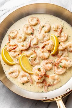 a skillet filled with shrimp and lemons on top of a marble countertop