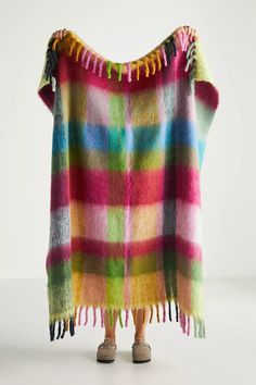 a multicolored plaid ponchle with tassels on the shoulders and feet