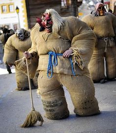 a group of people dressed in costumes and holding brooms on the street while standing next to each other