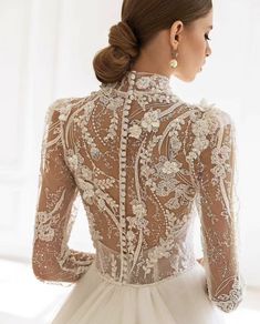 a woman wearing a wedding dress with an open back and sheer lace detailing on it