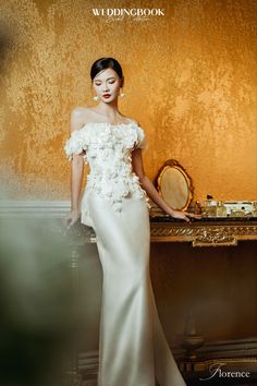 a woman in a white dress standing next to a table