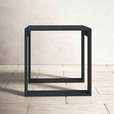 a black square table sitting on top of a white tiled floor next to a wall