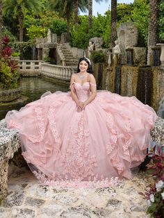 Captivate the room in this floral lace applique long sleeveless dress with an A-line ruffled skirt from LizLuo Quince by the House of Wu 26112. Make a statement in this ruffled Quinceanera ball gown. The classic neckline and corseted bodice are fully covered with stunning lace applique. Delicate shoulder straps are added. The full ball gown skirt showcases cascades of soft tulle ruffles and lace applique. A side bow is added for a unique touch. House of Wu LizLuo Quince Collection Spring 2025 St Quinceanera Dresses For Brown Skin, Purple Pink Quinceanera Dresses, Huge Quinceanera Dresses, Charro Pink Quinceanera Dresses, Bow Ball Gown, Quinceañera Dress Ideas, Pink Quinceanera Dresses Long Tail, Quince Dress Styles, Light Pink Xv Dresses