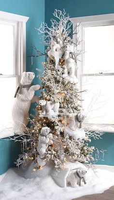 a white christmas tree in the corner of a room with blue walls and snow on it