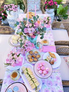 a table topped with lots of food and flowers next to a vase filled with pink flowers