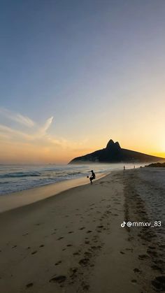 the sun is setting at the beach with footprints in the sand and people walking on the shore