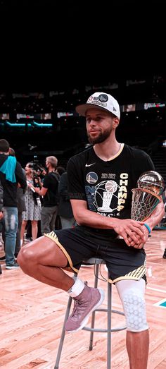 a man sitting on top of a chair holding a basketball trophy in front of him