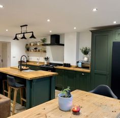 a kitchen with green cabinets and wooden counter tops