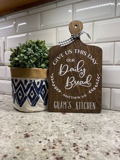 a wooden sign that says give us this day our daily bread and a potted plant