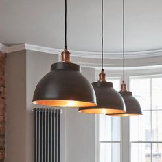 three pendant lights hanging from the ceiling in a room with windows and radiator