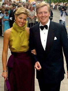 a man in a tuxedo standing next to a woman wearing a purple dress