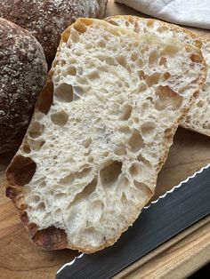 two loaves of bread sitting on top of a cutting board next to a knife