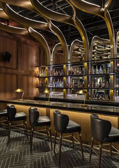 a bar with black leather chairs and wooden shelves