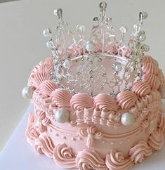 there is a pink cake with a tiara on top