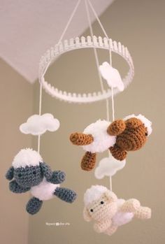 three crocheted stuffed animals hanging from a white circular chandelier with clouds in the background