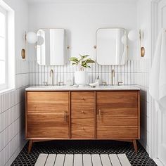 a bathroom with two sinks, mirrors and a rug on the floor in front of it