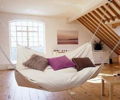 a white hammock hanging from the ceiling in a room with wood flooring