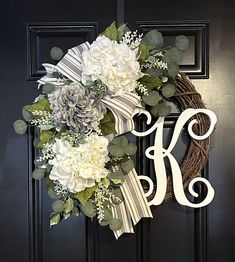 a monogrammed wreath with white flowers and greenery hangs on the front door