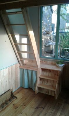 a room with wooden flooring and stairs leading up to the second floor, next to a window