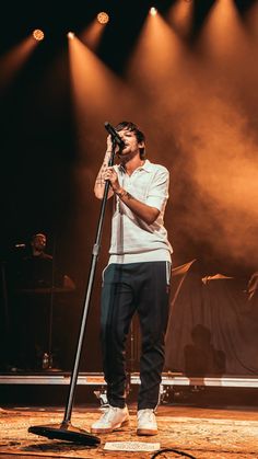 a man holding a microphone while standing on top of a stage