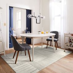 a dining room table with chairs and a rug on the floor in front of it