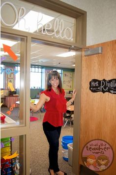 a woman standing in front of a door with her hand up and pointing at the camera