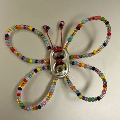 a butterfly made out of beads on a white surface with a string attached to it