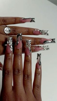 a woman's hand with pink nail polish and silver decorations on her nails,