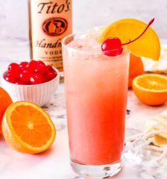 a pink drink with oranges and cherries next to it