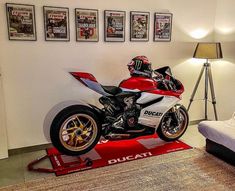 a red and white motorcycle sitting on top of a bed in a room with pictures above it