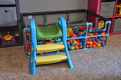 a child's plastic chair and toys in a playroom with bins full of balls