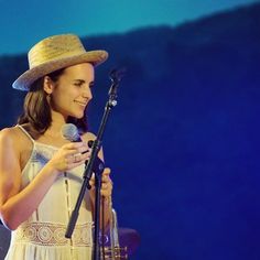 a woman wearing a hat and holding a microphone