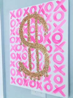 a pink and gold monogrammed wall hanging on the side of a white door