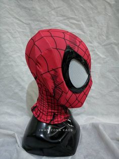 a spider - man mask is sitting on top of a black headpiece with mesh covering it's face