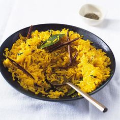 a plate full of rice and vegetables on a white table cloth with a spoon in it