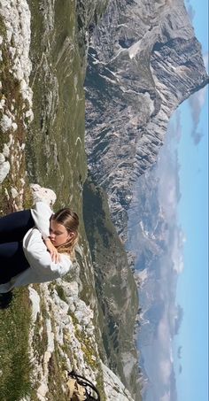 a woman sitting on the edge of a cliff