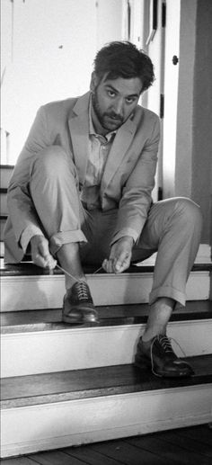 a man in a suit sitting on the steps with his foot propped against his shoe