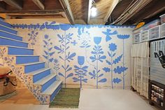 a room with blue and white flowers painted on the walls, carpeted flooring and stairs