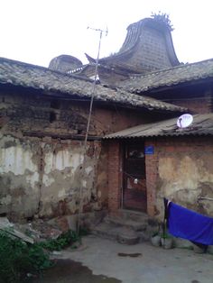 an old brick building with a blue tarp on the front door and a satellite dish mounted to it's roof