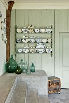 there are many plates and vases on the shelf next to each other in this room