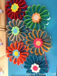 colorful paper flowers are hanging on the wall